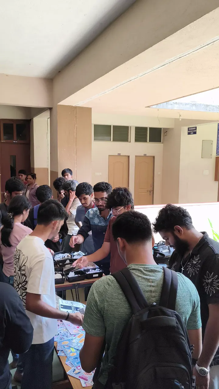 Students gathered around the stall table in a college corridor